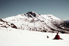 Walker sits on snow near Naturalist Peak