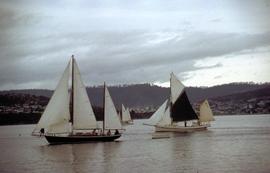 Yachts on river, one with black sail