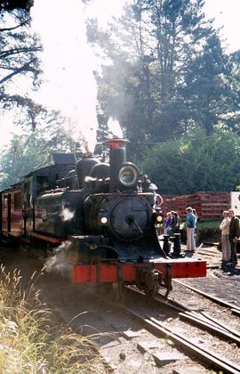 Steam train pulls into railyard near piles of sleepers